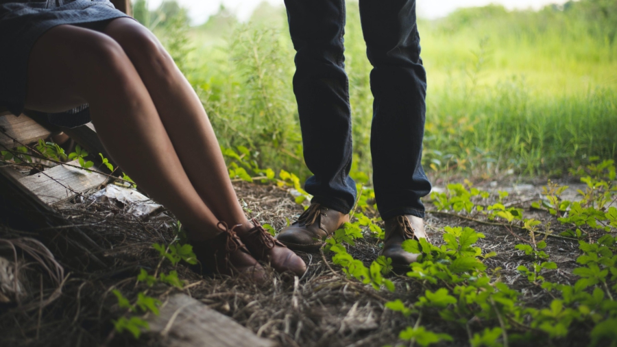 nainen istuu kivellä mies seisoo