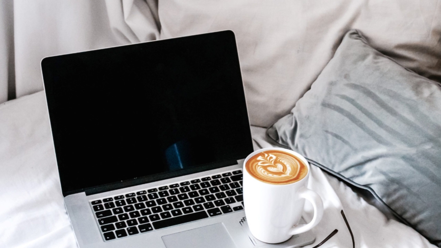 tietokone sängyllä ja kahvikuppi