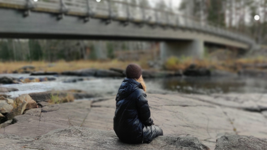 Henkilö istuu kalliolla