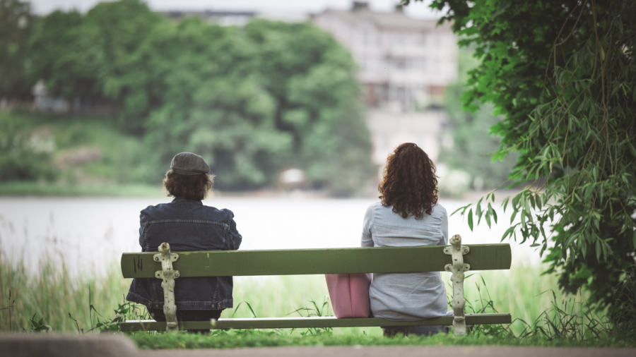 Kaksi henkilö istuu penkin eri päissä