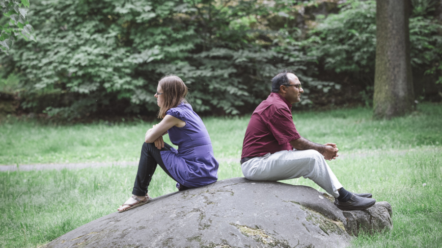 Nainen ja mies kivellä selät vastakkain