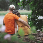 Pari istumassa puunrungolla nojaamassa toisiinsa