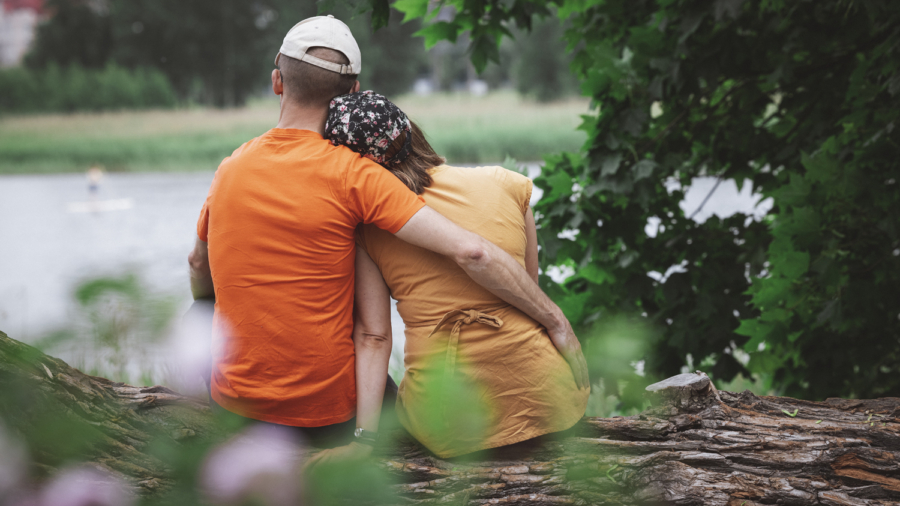 Pari istumassa puunrungolla nojaamassa toisiinsa